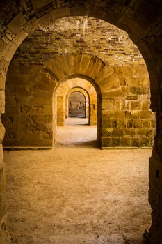 Italy - Old castle of Syracuse in Siciliy. Archs made of stone in perspective.