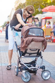 Young father talking to his baby in a stroller, while talking a walk downtown.