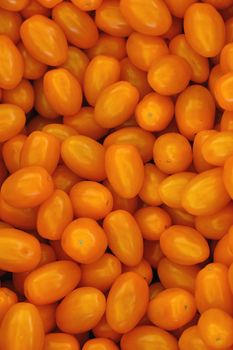 Close up fresh yellow cherry tomatoes at retail display of farmers market, high angle view