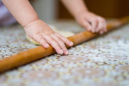 Hands baking dough with rolling pin on table. little chef  bake in kitchen.