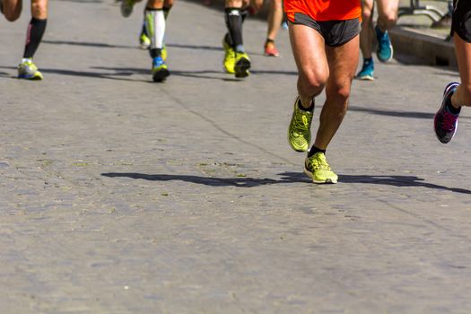 Detail of a group of runners during a city marathon. Legs and sneakers. Muscles under stress. Sport concept