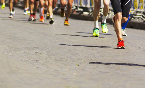 Detail of a group of runners during a city marathon. Legs and sneakers. Muscles under stress. Sport concept