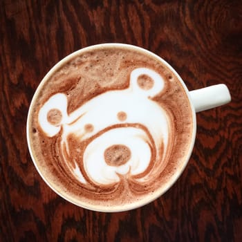 Cute teddy bear drawing on a cup of tasty hot chocolate.