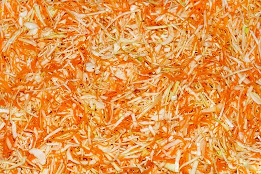 Shredded cabbage and carrots background. Preparing homemade sauerkraut - fermented cabbage and carrots, rustic winter food.