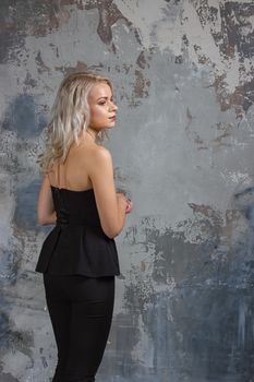 Portrait of a girl with long hair in youth clothes, Young beautiful girl near the wall her back