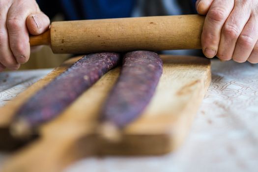 Closeup of man hands rolling over homemade sausages to make them flat for drying