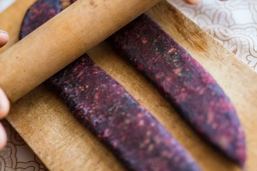 Closeup of man hands rolling over homemade sausages to make them flat for drying