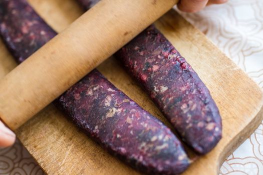 Closeup of man hands rolling over homemade sausages to make them flat for drying