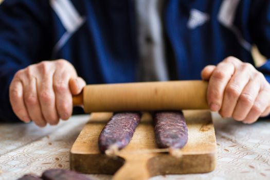 Closeup of man hands rolling over homemade sausages to make them flat for drying