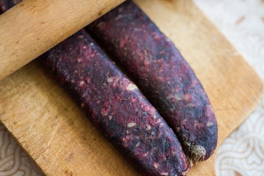 Closeup of man hands rolling over homemade sausages to make them flat for drying