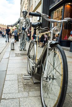 a man in a mirror suit with a suitcase and a bicycle is calling to the Krakow store