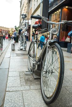 a man in a mirror suit with a suitcase and a bicycle is calling to the Krakow store