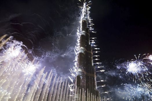 Festive firework in Dubai. Beautiful colorful holiday fireworks in the evening sky with majestic clouds, long exposure