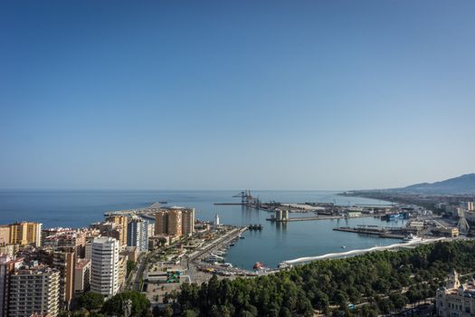 City skyline and harbour, sea port of Malaga overlooking the sea ocean in Malaga, Spain, Europe on a bright summer day with blue skies with trees