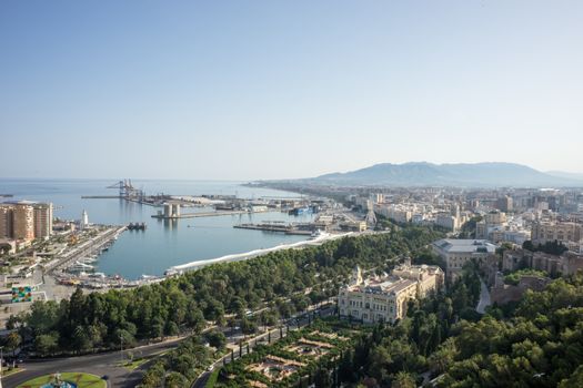 City skyline and harbour, sea port of Malaga overlooking the sea ocean in Malaga, Spain, Europe on a bright summer day with blue skies with trees