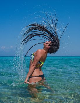 Beautiful girl splashing water with her hair in the sea or ocean.