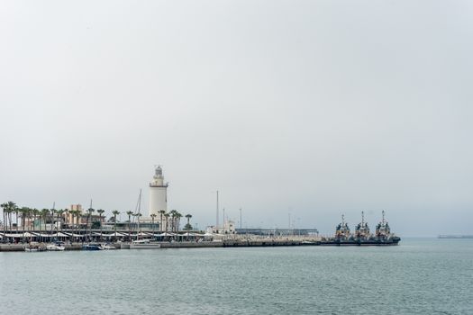 Lighthouse and ships along the coastline at Malaga, Spain, Europe on a cloudy morning