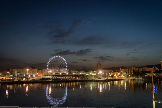View of Malaga city  and giant wheel from harbour, Malaga, spain, Europe at night with reflections