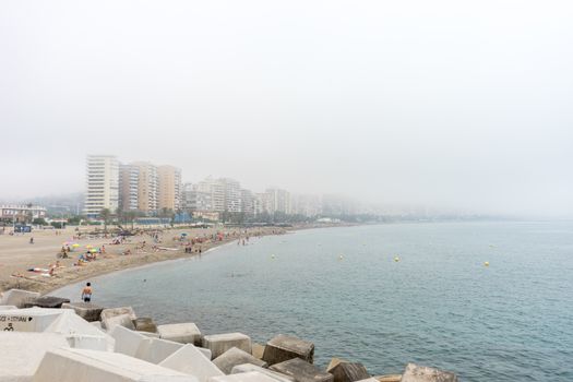 The building along the coastline at Malagueta beach covered by fog in Malaga, Spain, Europe on a foggy morning