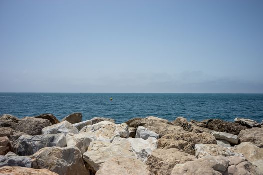 Rocks against the green ocean at Malagueta beach in malaga, Spain, Europe with clear sky in the morning