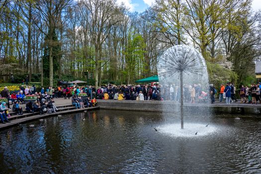 Keukenhoff, Netherlands - April 17 : The Keukenhoff Tulip Gardens on April 17, 2016. Tourists gather near the water fountain  on a summer day