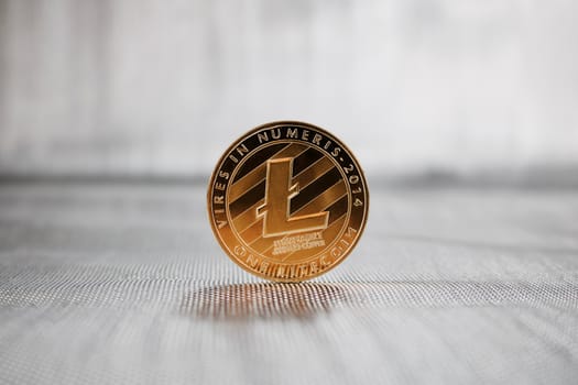 Cryptocurrency physical gold Litecoin coin on the silver background. Money concept.