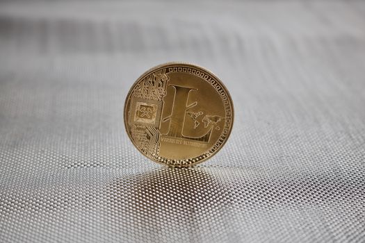 Digital currency physical gold litecoin coin on the silver background.