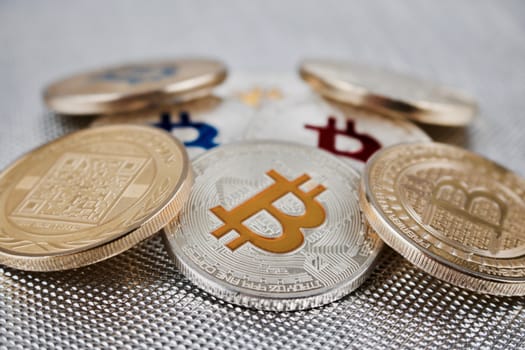 Cryptocurrency physical silver and gold bitcoin coins on the silver background.