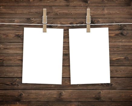 Paper cards hanging on a clothesline with clothespins on wood background