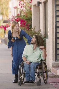 Woman talking with friend in wheelchair on sidewalk