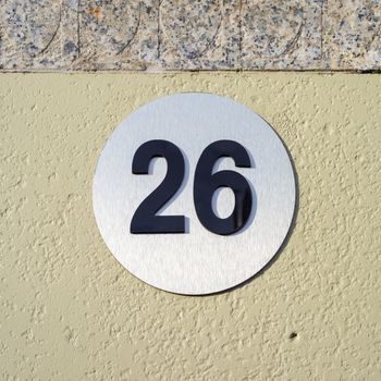 Modern house number twenty six (26) on a metal plate