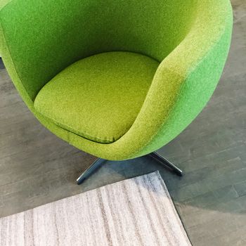 Trendy green armchair on dark wooden floor. Modern furniture.