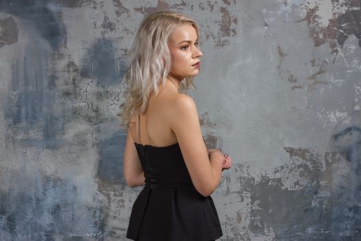 Portrait of a girl with long hair in youth clothes, Young beautiful girl near the wall her back