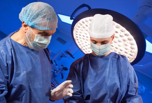 Couple of doctors are performing surgery in modern operating room.