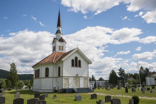 white wooden stave church near Leira in Norway with cemetery