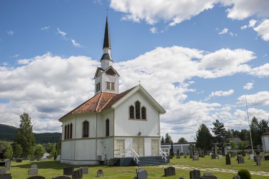 white wooden stave church near Leira in Norway with cemetery
