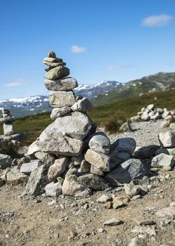 balanced stack of stones at Eidfjorden, Norway with snow and mountains as background