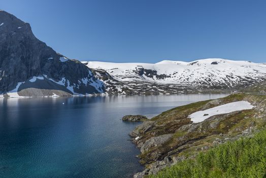 The famous road in Norway also called road 51 or the bygdin vegen near Bismo with blue water  in the fjord and white snoiw on the mountains in summer