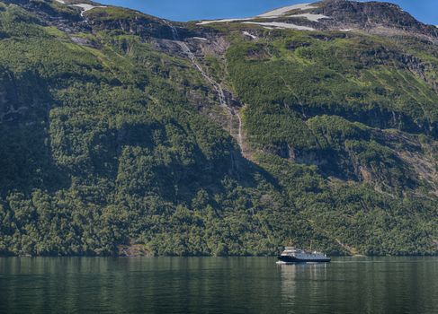 people on cruise boat at the famous geiranger fjord waterfalls in norway