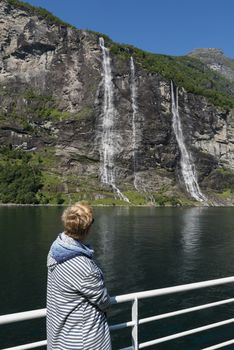 woman on a ferry boat looking at the waterfall at the geiranger fjord in norway
