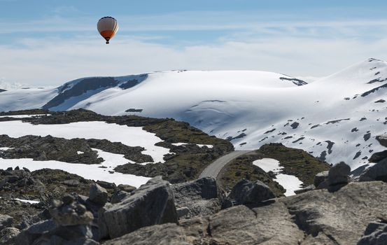 hot air balloon above the dalsnibba or road 63 touristic road to the high view of the geirangerfjord in norway with snow in summer on the tops of the mountains