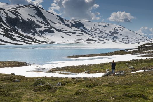 woman looking at the beautifull nature at the gamle strynefjellsvegen one of the most beautifull auto roads in norway with snow in summer 