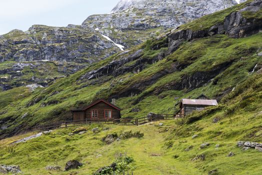 wooden house on the hills of the Jostedalsbreen nature park  in summer with snow on the mountains
