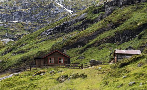wooden house on the hills of the Jostedalsbreen nature park  in summer with snow on the mountains