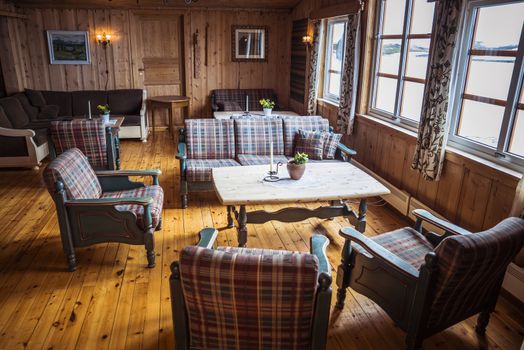 typical norway interior with outisde the snow on the mountains ans inside warm brown chairs and wooden table and floor
