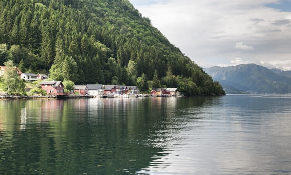 typical wooden houses in red orange and blue in the village called Vik at the sognefjord in Norway