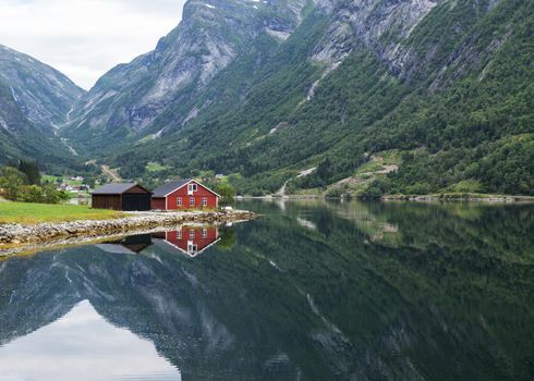 typical norway fjord with red wooden houses and reflection in the water