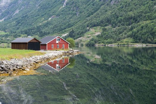 typical norway fjord with red wooden houses and reflection in the water