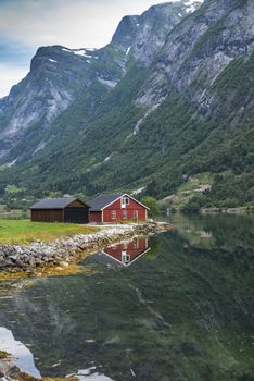typical norway fjord with red wooden houses and reflection in the water