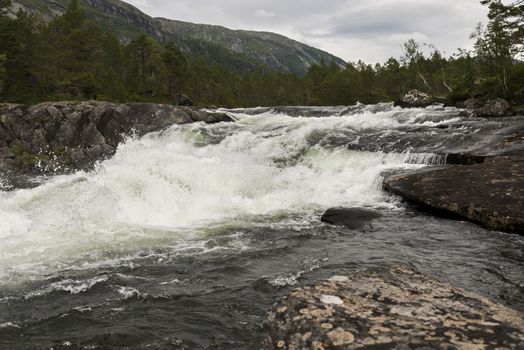 likholefossen waterfall in norway with mountains as background